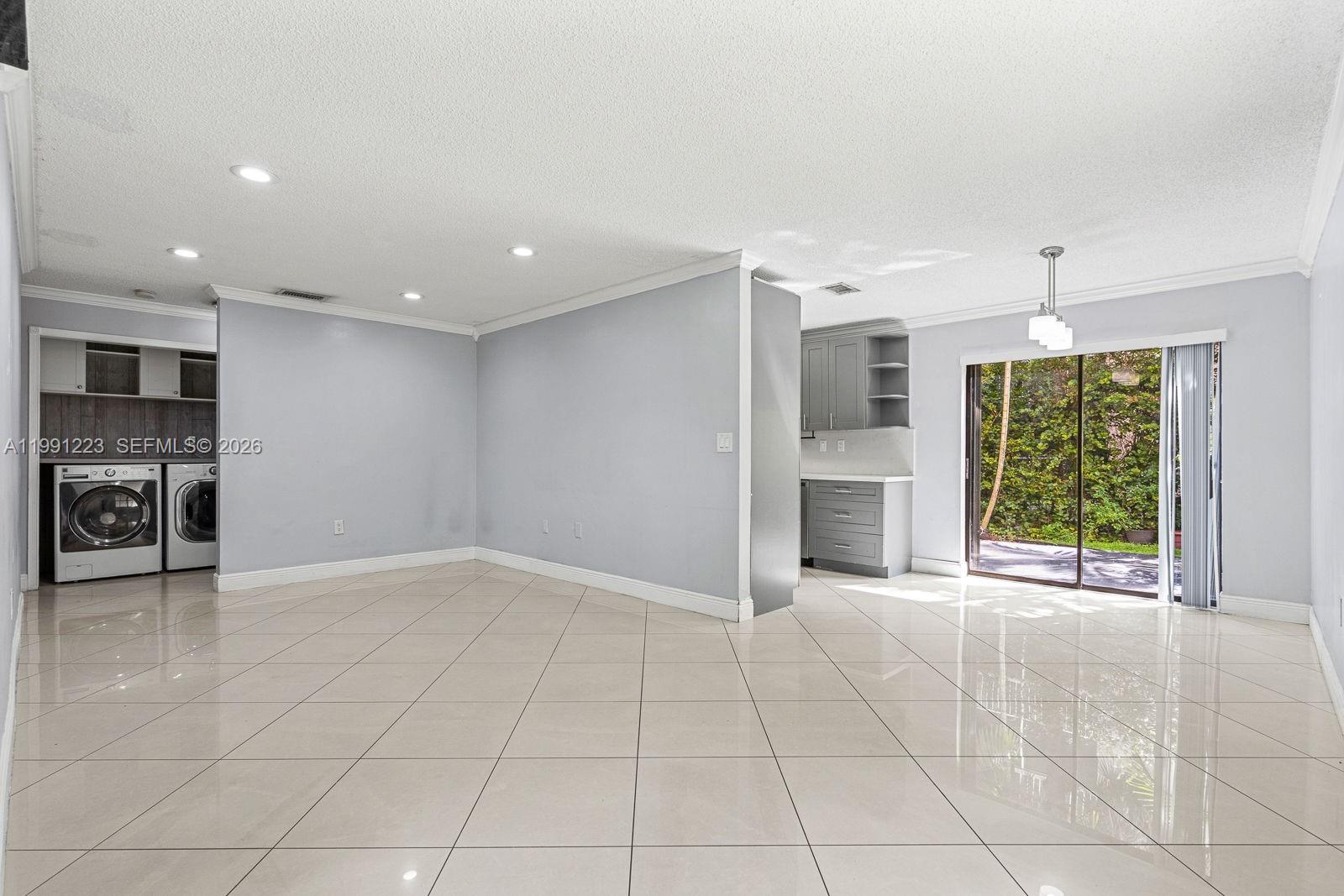 A bright, open-concept room features light-colored tile flooring, recessed lighting, and a sliding glass door — 6854 NW 173rd Dr # 210, Hialeah FL 33015, HIALEAH, FL