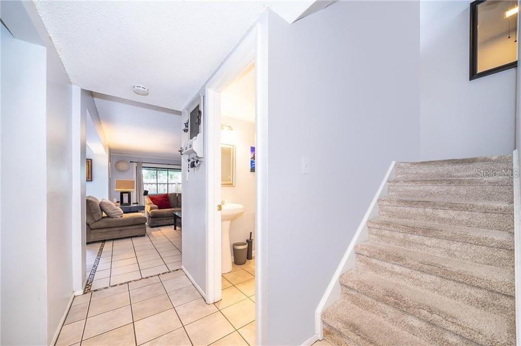A tiled entryway leads to a living room and a bathroom, with stairs on the right — 7470 CANFORD COURT UNIT 23, WINTER PARK, FL