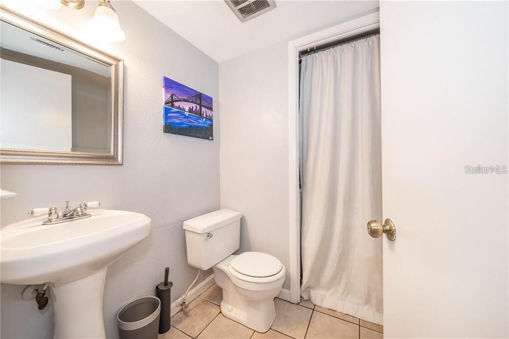 A bathroom features a pedestal sink, a toilet, and a shower curtain over the doorway — 7470 CANFORD COURT UNIT 23, WINTER PARK, FL