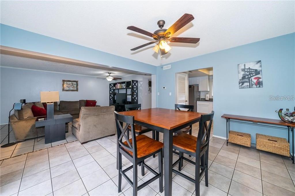 A dining area with a wooden table and chairs opens into a living room — 7470 CANFORD COURT UNIT 23, WINTER PARK, FL