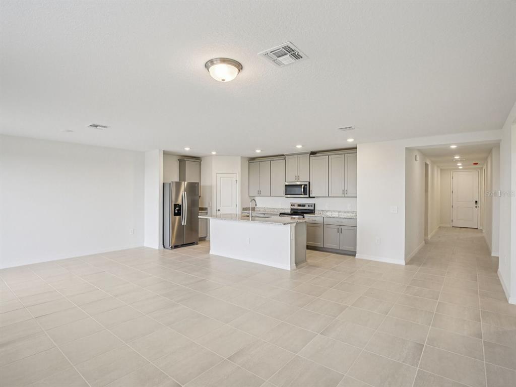 An open-concept kitchen with gray cabinets, stainless steel appliances, and a central island — 823 SUNSHOWER DRIVE, LADY LAKE, FL