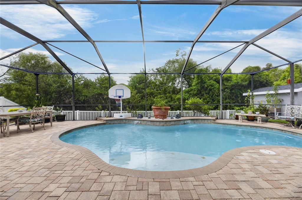 A screened-in pool area with a basketball hoop, patio furniture, and a stone paver deck — 13311 GRAHAM YARDEN DRIVE, RIVERVIEW, FL