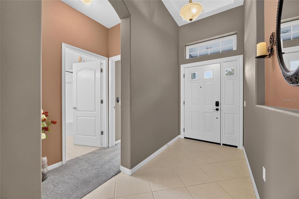 An entryway features beige tile flooring, light brown walls, a white front door, and carpeted hallway — 13311 GRAHAM YARDEN DRIVE, RIVERVIEW, FL