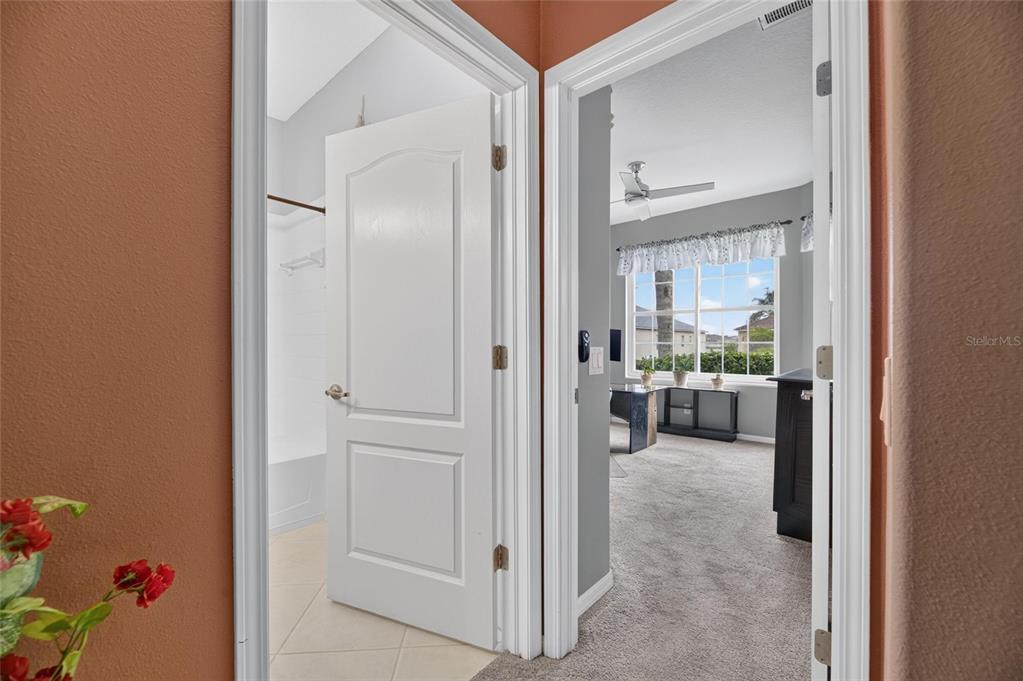A view through two doorways showing a tiled bathroom and a carpeted office space — 13311 GRAHAM YARDEN DRIVE, RIVERVIEW, FL