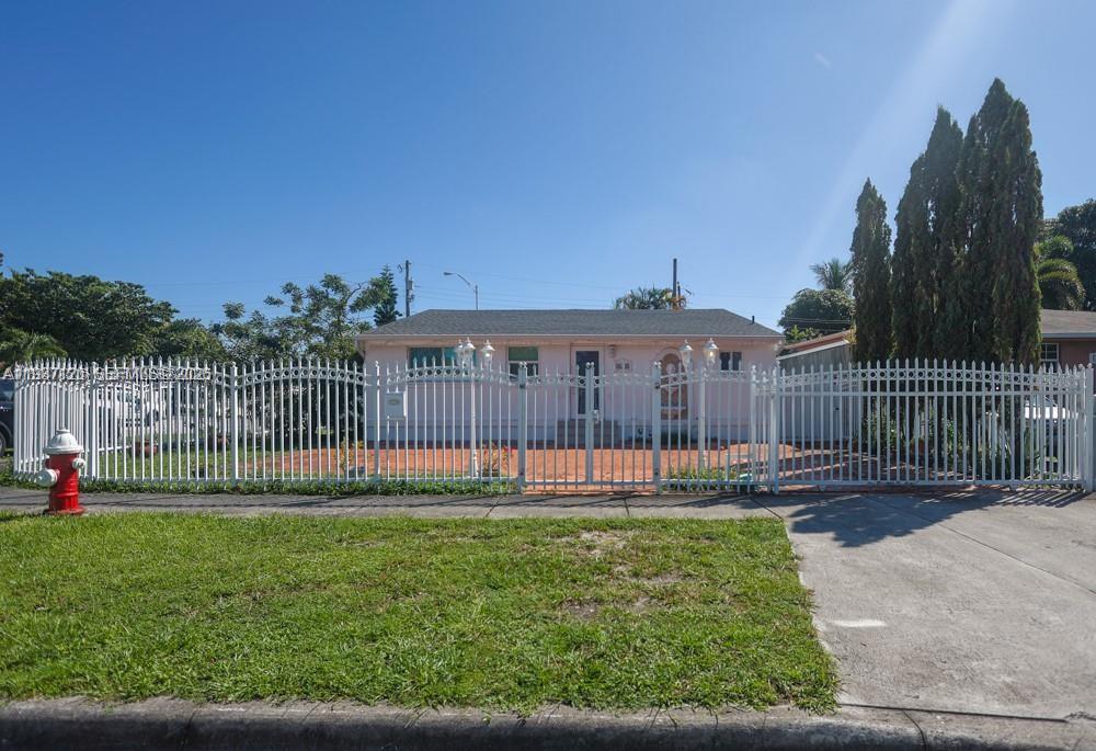A single-story pink house sits behind a white metal fence with a front yard — 3495 W 2nd Ave, Hialeah FL 33012, HIALEAH, FL