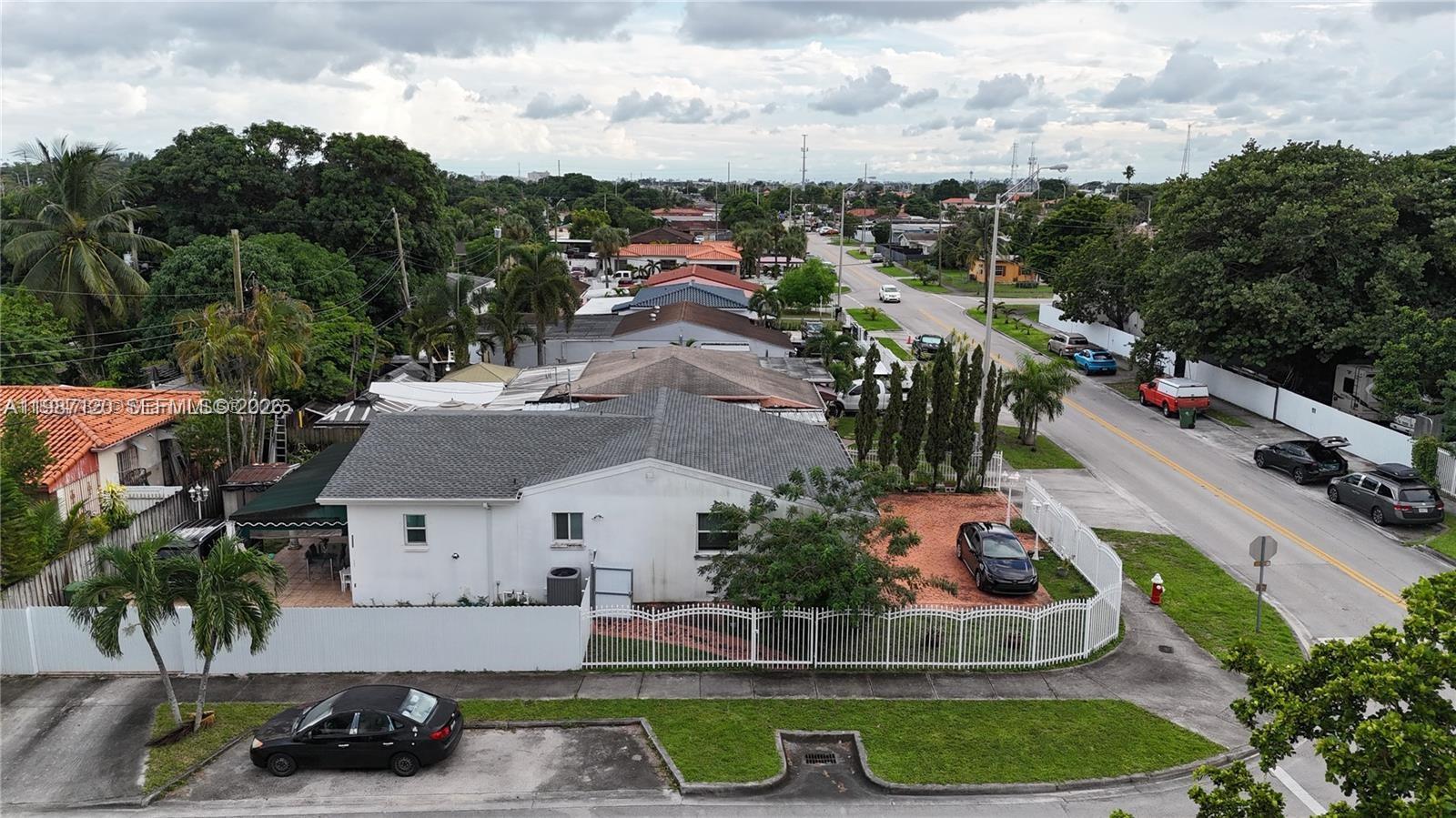 An aerial view shows a white house with a gray roof, fenced yard, and driveway — 3495 W 2nd Ave, Hialeah FL 33012, HIALEAH, FL