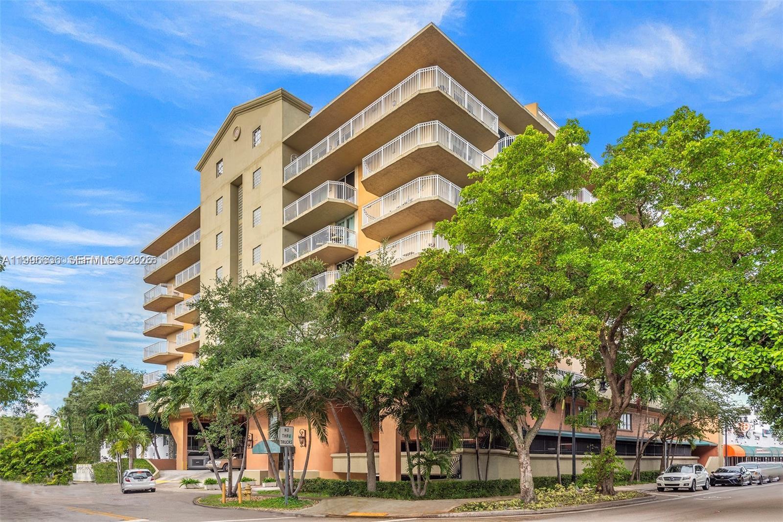 A multi-story residential building with balconies stands behind trees and a street — 1650 Coral Way # 601, Miami FL 33145, MIAMI, FL