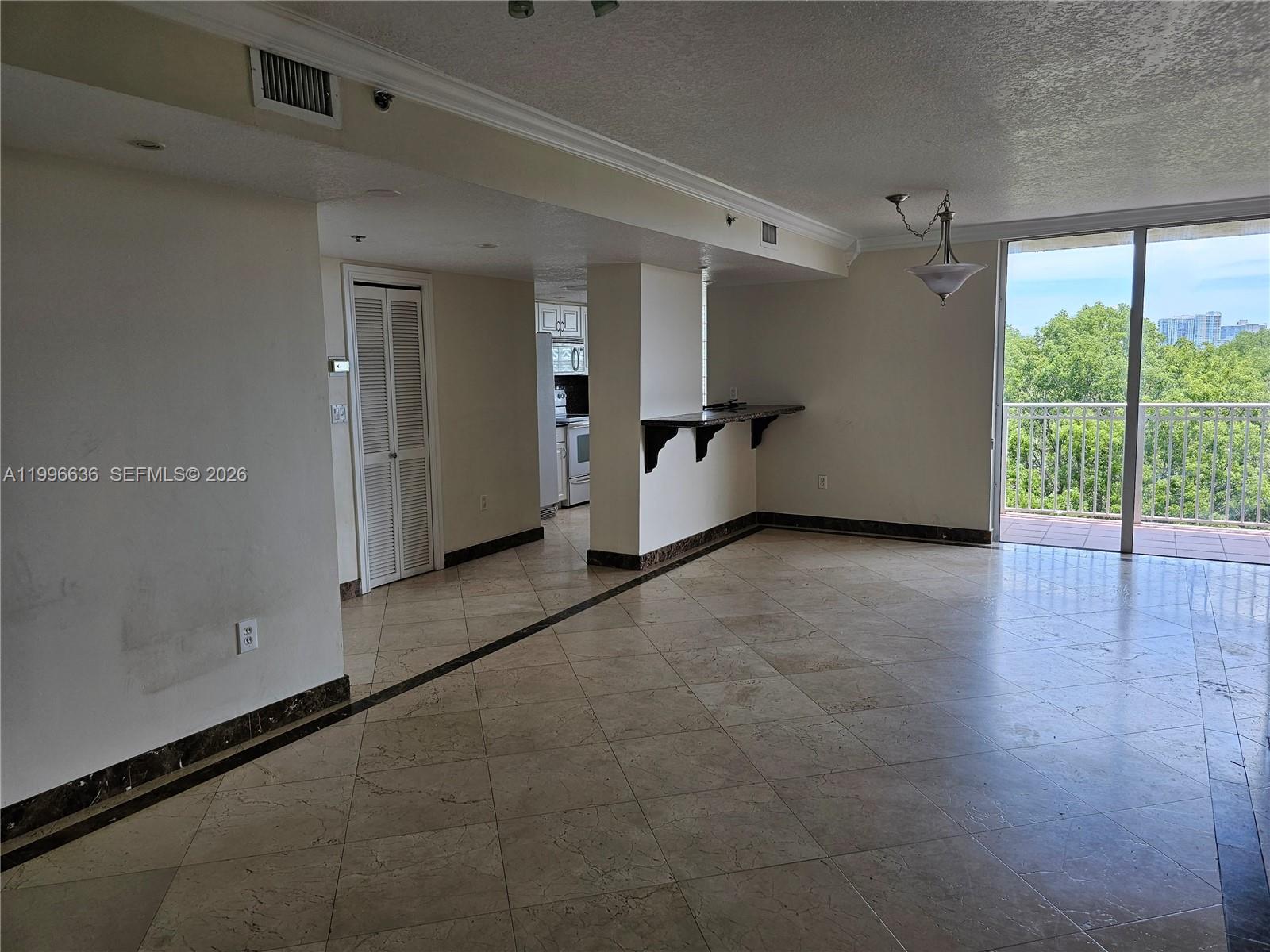 An open living area features tile flooring, a breakfast bar, and a balcony with trees — 1650 Coral Way # 601, Miami FL 33145, MIAMI, FL