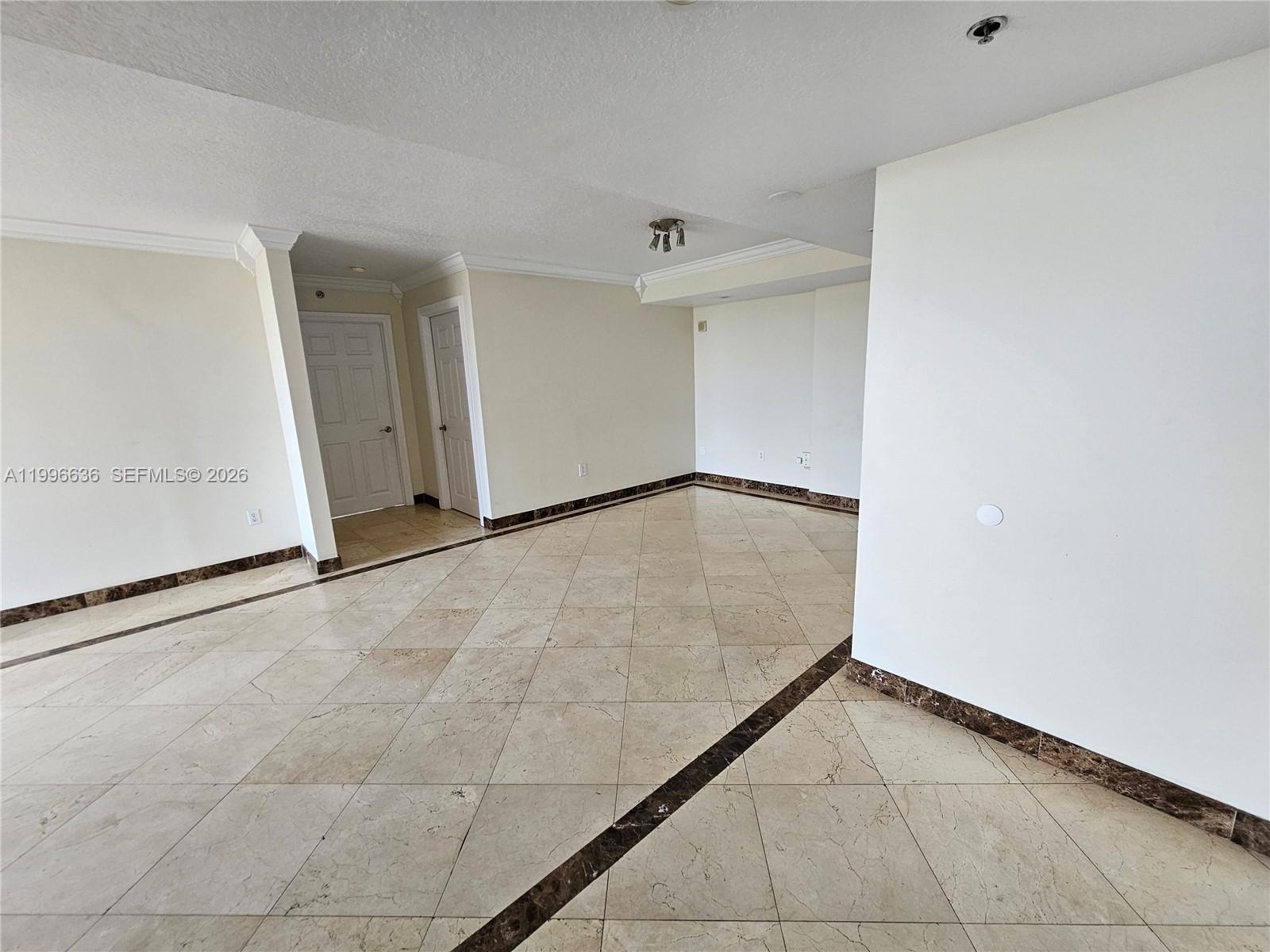 An empty room features beige tiled floors with dark decorative borders and white walls — 1650 Coral Way # 601, Miami FL 33145, MIAMI, FL