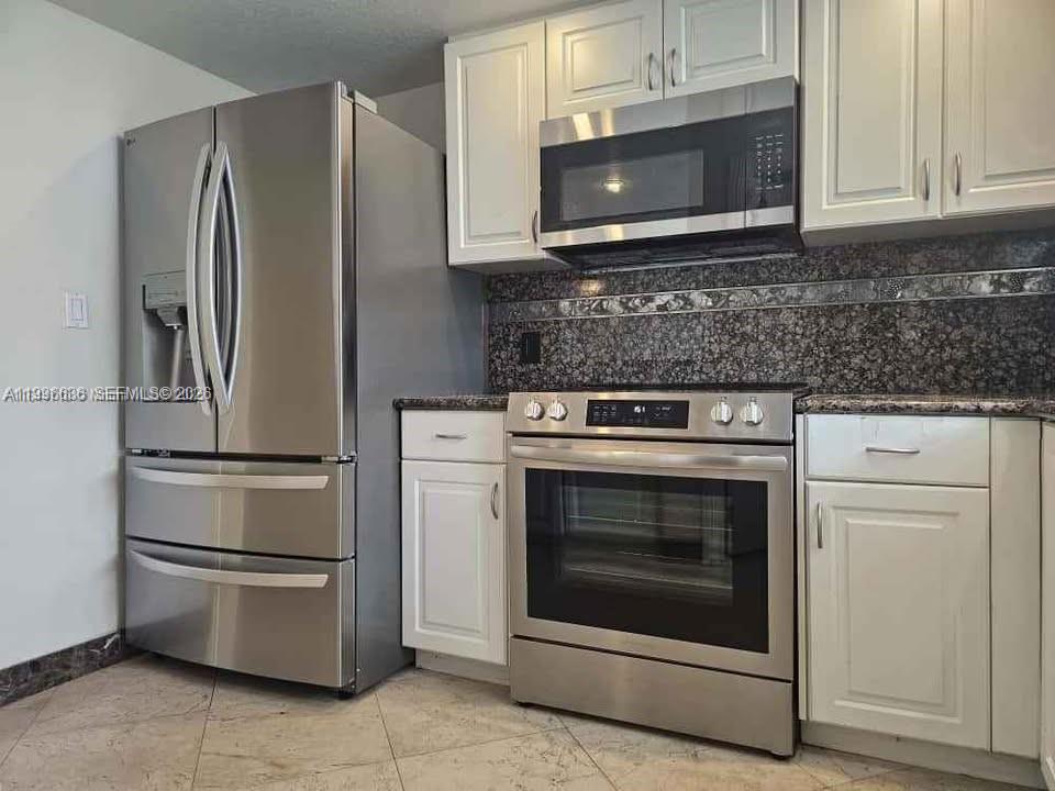 A kitchen features stainless steel appliances, white cabinets, and a dark granite backsplash — 1650 Coral Way # 601, Miami FL 33145, MIAMI, FL
