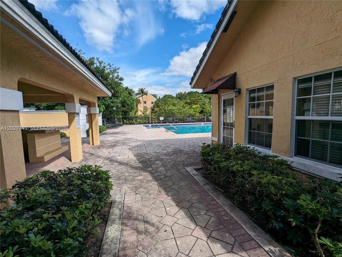 An outdoor patio area features a swimming pool, paved walkways, and beige building exteriors — 4055 W Mcnab Rd # H112, Pompano Beach FL 33069, POMPANO BEACH, FL