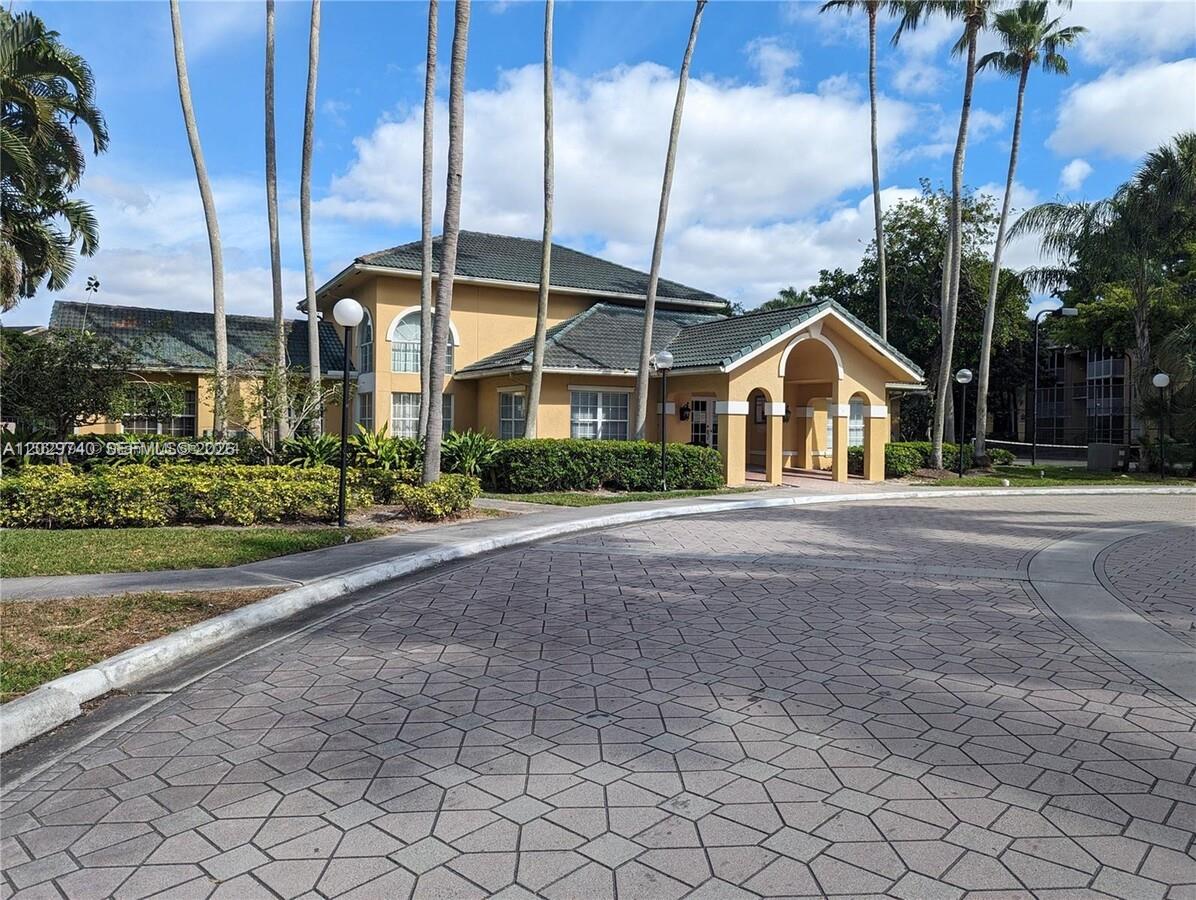 A two-story yellow building with a tiled roof stands behind a paved circular driveway — 4055 W Mcnab Rd # H112, Pompano Beach FL 33069, POMPANO BEACH, FL