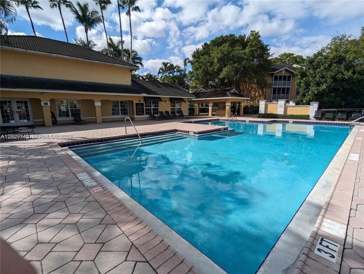 A swimming pool with a paved deck is situated in front of a multi-story building — 4055 W Mcnab Rd # H112, Pompano Beach FL 33069, POMPANO BEACH, FL