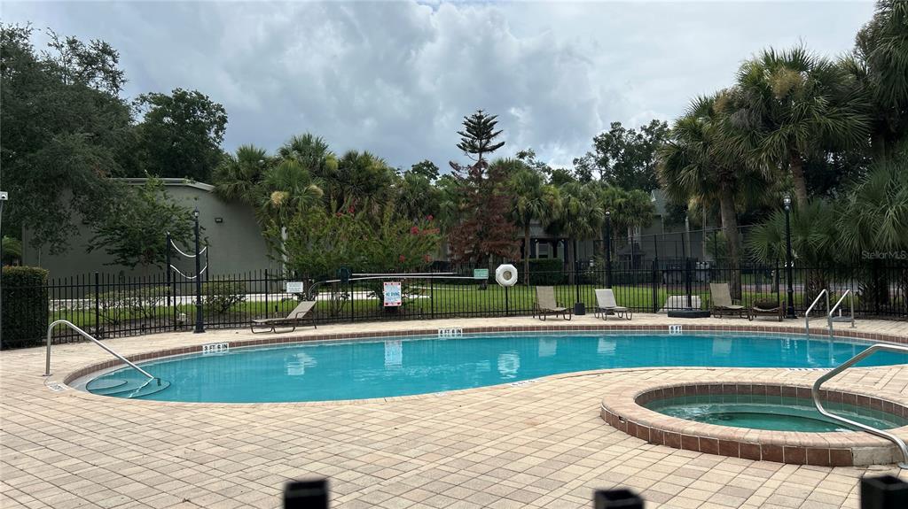 An outdoor swimming pool and hot tub are enclosed by a black metal fence — 6010 WESTGATE DRIVE UNIT 303, ORLANDO, FL