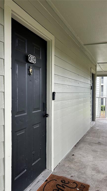 A black apartment door labeled 303 is situated on a covered outdoor walkway — 6010 WESTGATE DRIVE UNIT 303, ORLANDO, FL