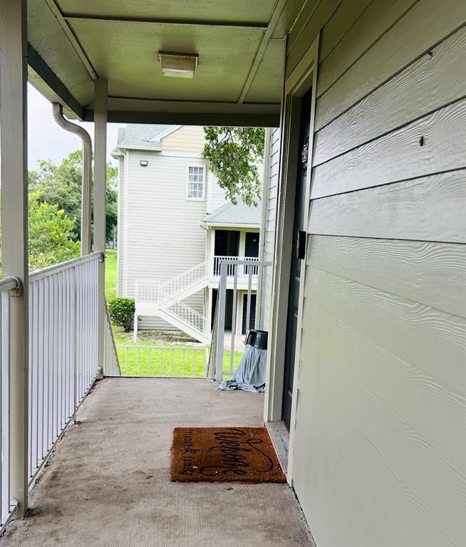 An outdoor apartment balcony features a concrete floor, a welcome mat, and a metal railing — 6010 WESTGATE DRIVE UNIT 303, ORLANDO, FL