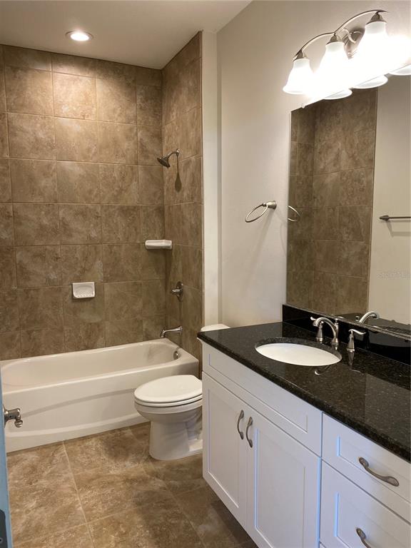A bathroom features a tiled shower-tub combo, a white vanity with a dark countertop, and a toilet — 1793 NAMATKA AVENUE, NORTH PORT, FL