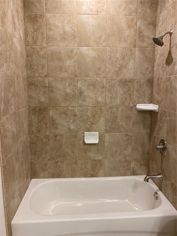 A bathtub and shower combination with beige tile walls and chrome fixtures — 1793 NAMATKA AVENUE, NORTH PORT, FL