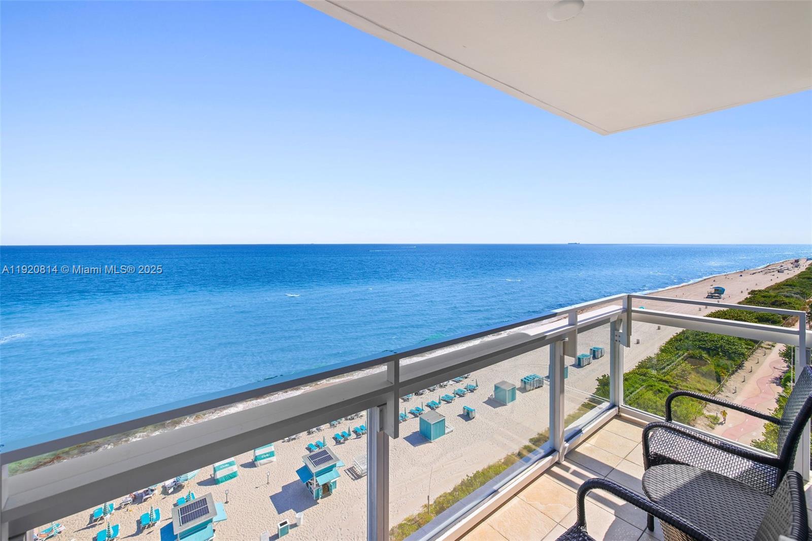 A balcony with outdoor seating overlooks a sandy beach and the ocean — 6801 Collins Ave, Miami Beach FL 33141, MIAMI BEACH, FL