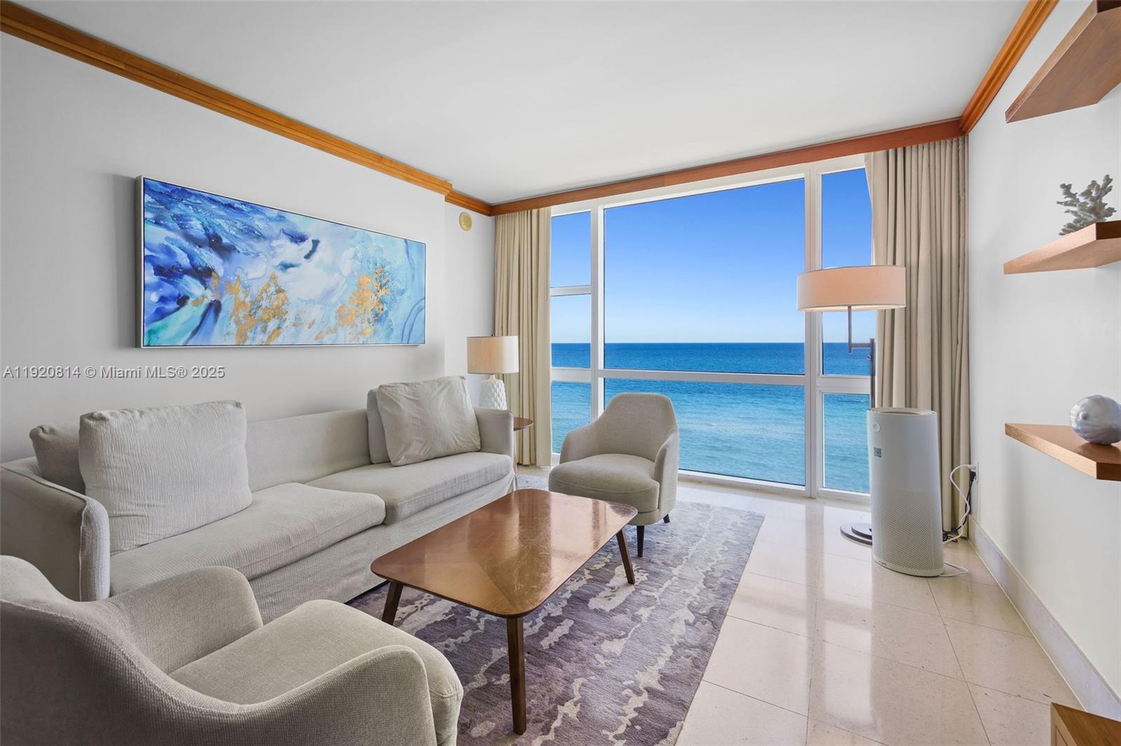 A living room features a sofa, armchairs, a coffee table, and floor-to-ceiling ocean views — 6801 Collins Ave, Miami Beach FL 33141, MIAMI BEACH, FL