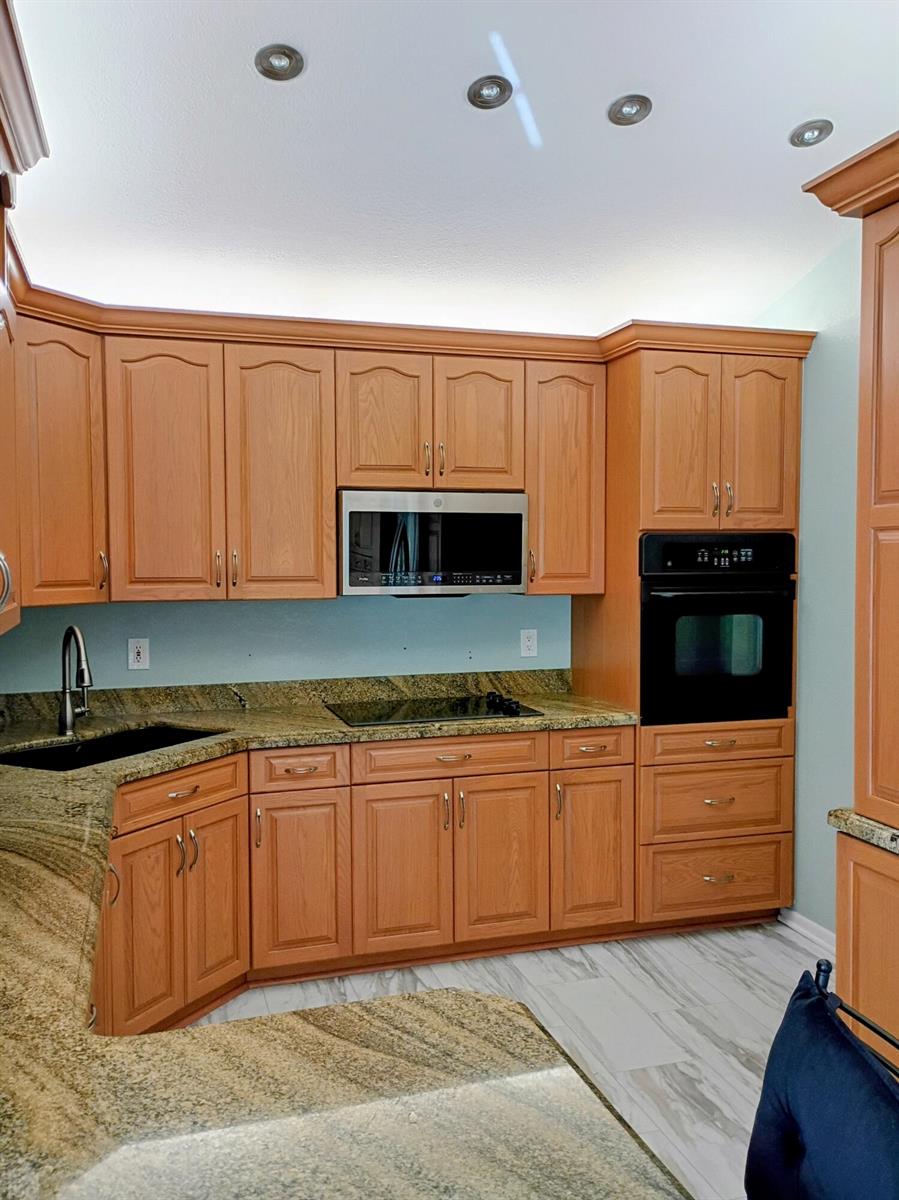 A kitchen features oak cabinets, granite countertops, a black oven, and a built-in microwave — 3451 Jog Park Drive, FL 33467, FL