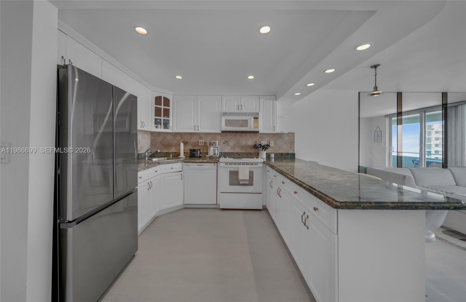 A white kitchen features stainless steel appliances, granite countertops, and recessed lighting — 465 Ocean Dr # 1102, Miami Beach FL 33139, MIAMI BEACH, FL