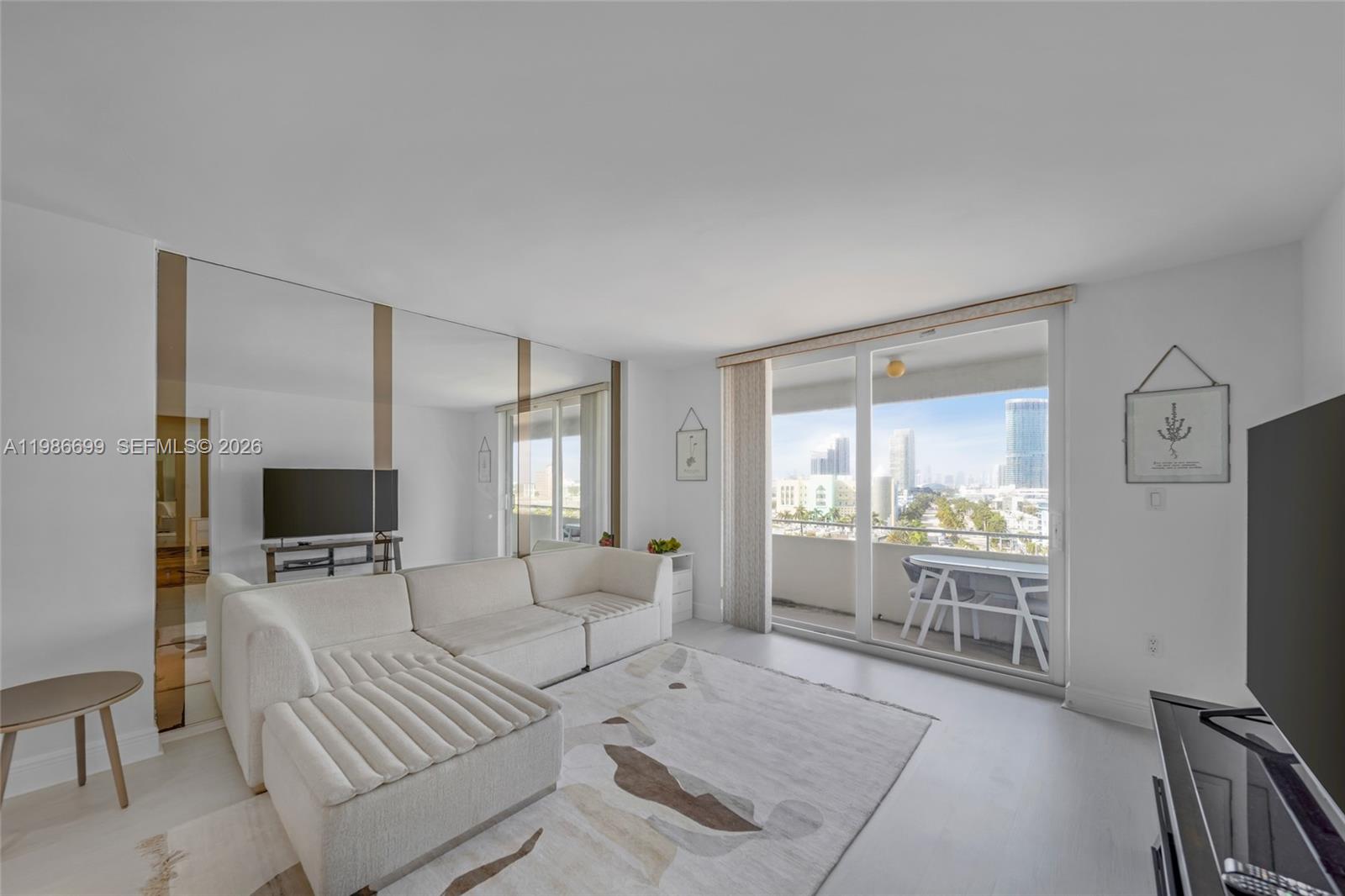 A living room features a white sectional sofa, a patterned rug, and a balcony view — 465 Ocean Dr # 1102, Miami Beach FL 33139, MIAMI BEACH, FL