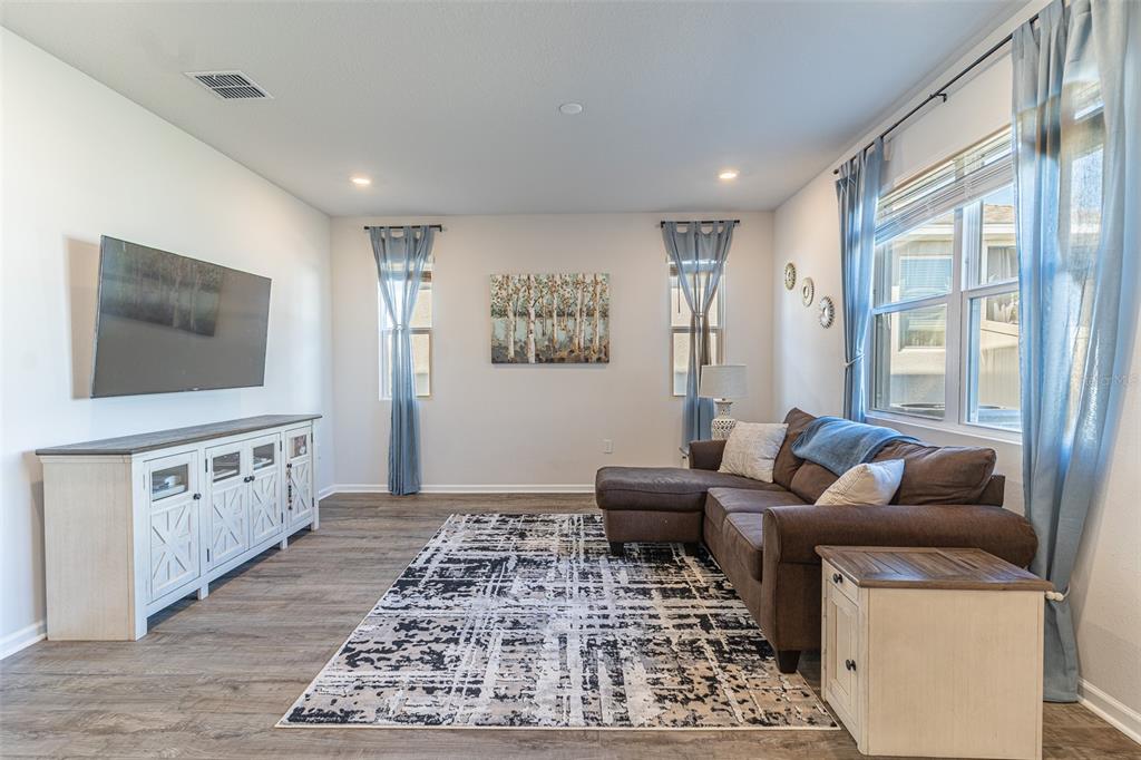 A living room features a brown sectional sofa, a television, and a patterned area rug — 1123 SUGARWOOD STREET, DAVENPORT, FL