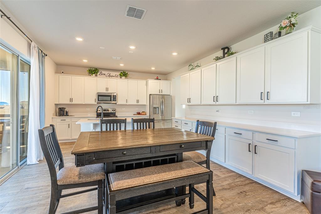 A kitchen features white cabinetry, a wooden dining table with chairs, and a sliding door — 1123 SUGARWOOD STREET, DAVENPORT, FL