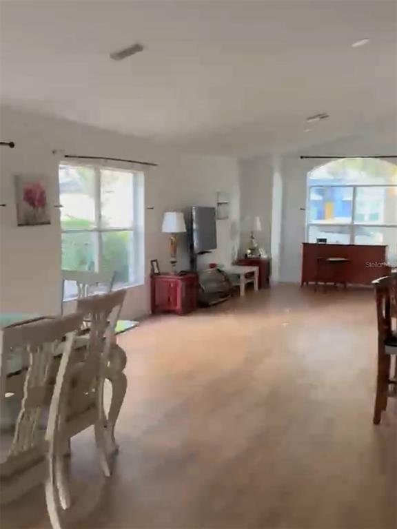 A living and dining area features light wood-look flooring, white walls, and multiple windows — 15909 GREEN COVE BOULEVARD, CLERMONT, FL