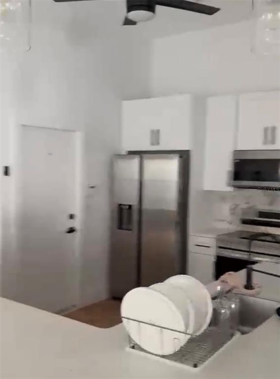 A kitchen features white cabinetry, stainless steel appliances, and a dish rack on the counter — 15909 GREEN COVE BOULEVARD, CLERMONT, FL