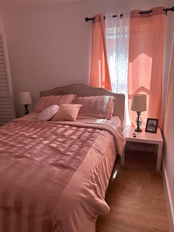 A bedroom features a bed with pink bedding, two bedside lamps, and peach-colored curtains — 15909 GREEN COVE BOULEVARD, CLERMONT, FL