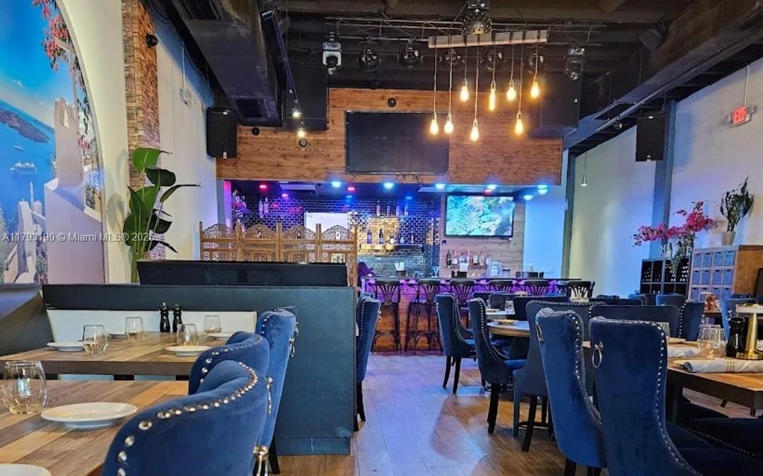 A restaurant interior features blue velvet chairs, wooden tables, a bar area, and pendant lighting — 1814 Harrison St, Hollywood FL 33020, HOLLYWOOD, FL