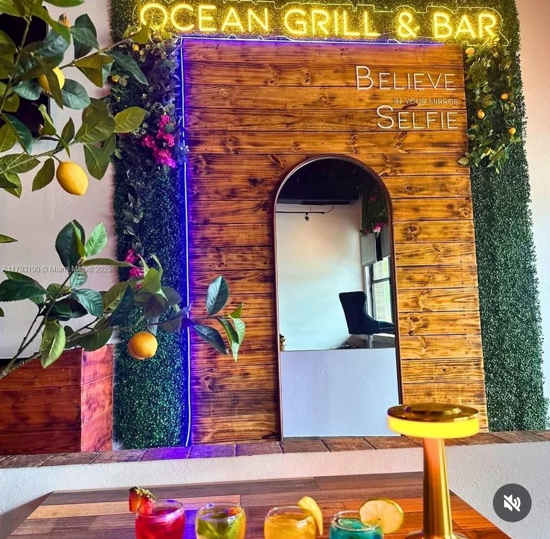 A wooden wall with an arched mirror, neon signage, and artificial greenery at a restaurant — 1814 Harrison St, Hollywood FL 33020, HOLLYWOOD, FL