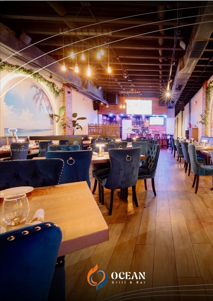 The interior of a restaurant features blue velvet chairs, wooden tables, and exposed ceiling beams — 1814 Harrison St, Hollywood FL 33020, HOLLYWOOD, FL