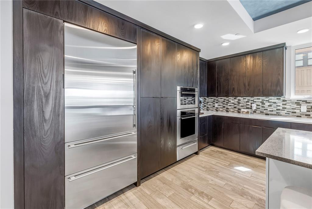A modern kitchen features dark wood cabinetry, stainless steel appliances, and light wood-look flooring — 19816 GULF BOULEVARD UNIT 201, INDIAN SHORES, FL