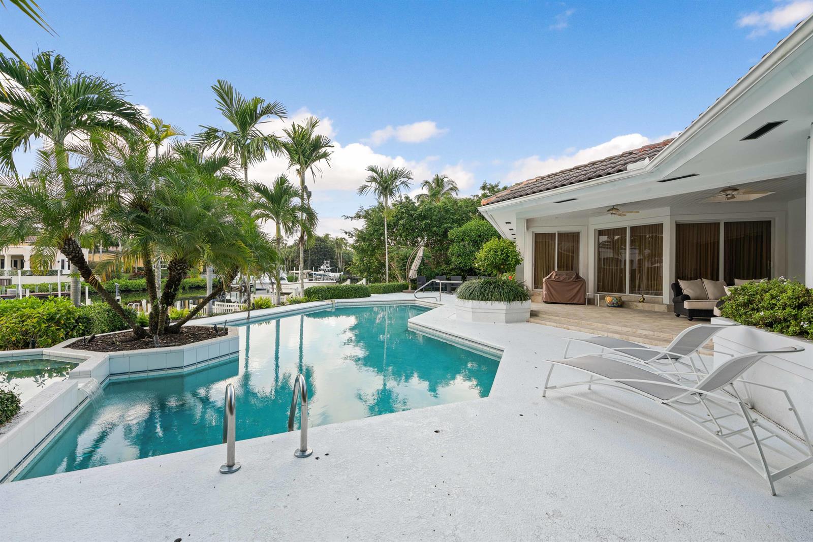 A swimming pool with a palm tree island sits on a patio beside a house — 351 Eagle Drive, Jupiter FL 33477, JUPITER, FL