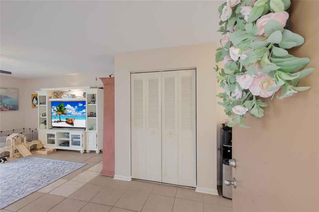 A view from an entryway into a living room with tile floors and a white entertainment center — 2727 75TH STREET W UNIT 7A11, BRADENTON, FL
