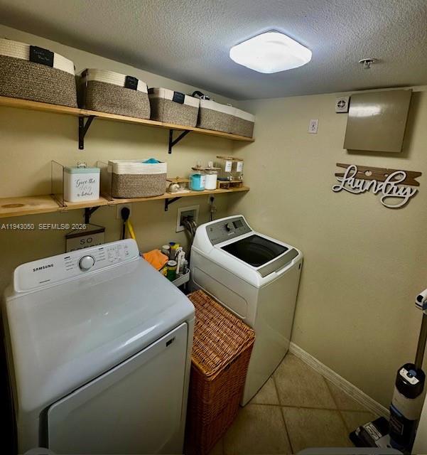 A laundry room features a washer, dryer, open shelving with storage baskets, and wall decor — 6434 Emerald Dunes Dr # 304, West Palm Beach FL 33411, WEST PALM BEACH, FL