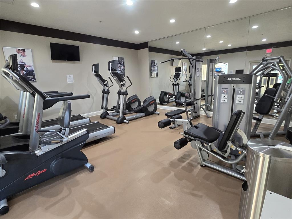 A fitness center featuring treadmills, elliptical machines, a weight station, and a large wall mirror — 7395 UNIVERSAL BOULEVARD UNIT 502, ORLANDO, FL