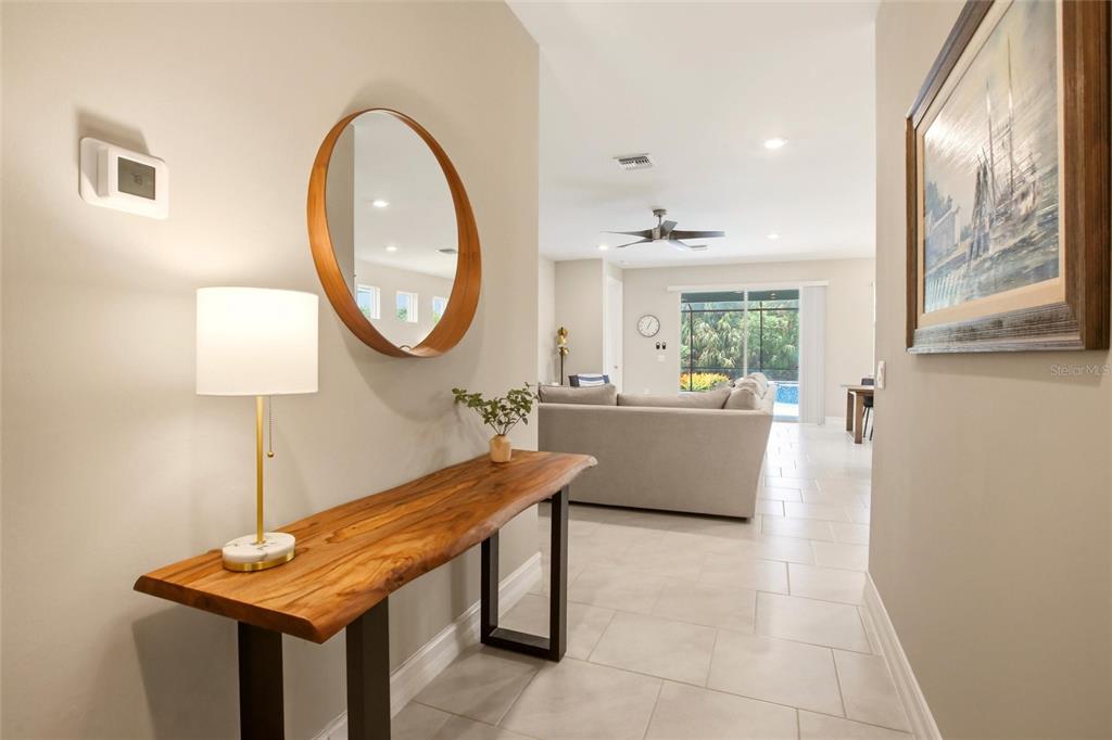 A foyer features a live-edge wood console table, a round mirror, and a table lamp — 844 HEATHER LAKE AVENUE, CAPE CORAL, FL