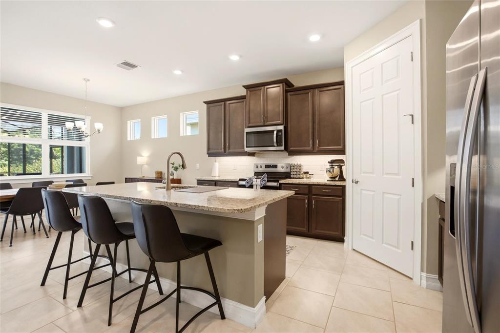 A kitchen features dark wood cabinets, granite countertops, a center island, and tile flooring — 844 HEATHER LAKE AVENUE, CAPE CORAL, FL