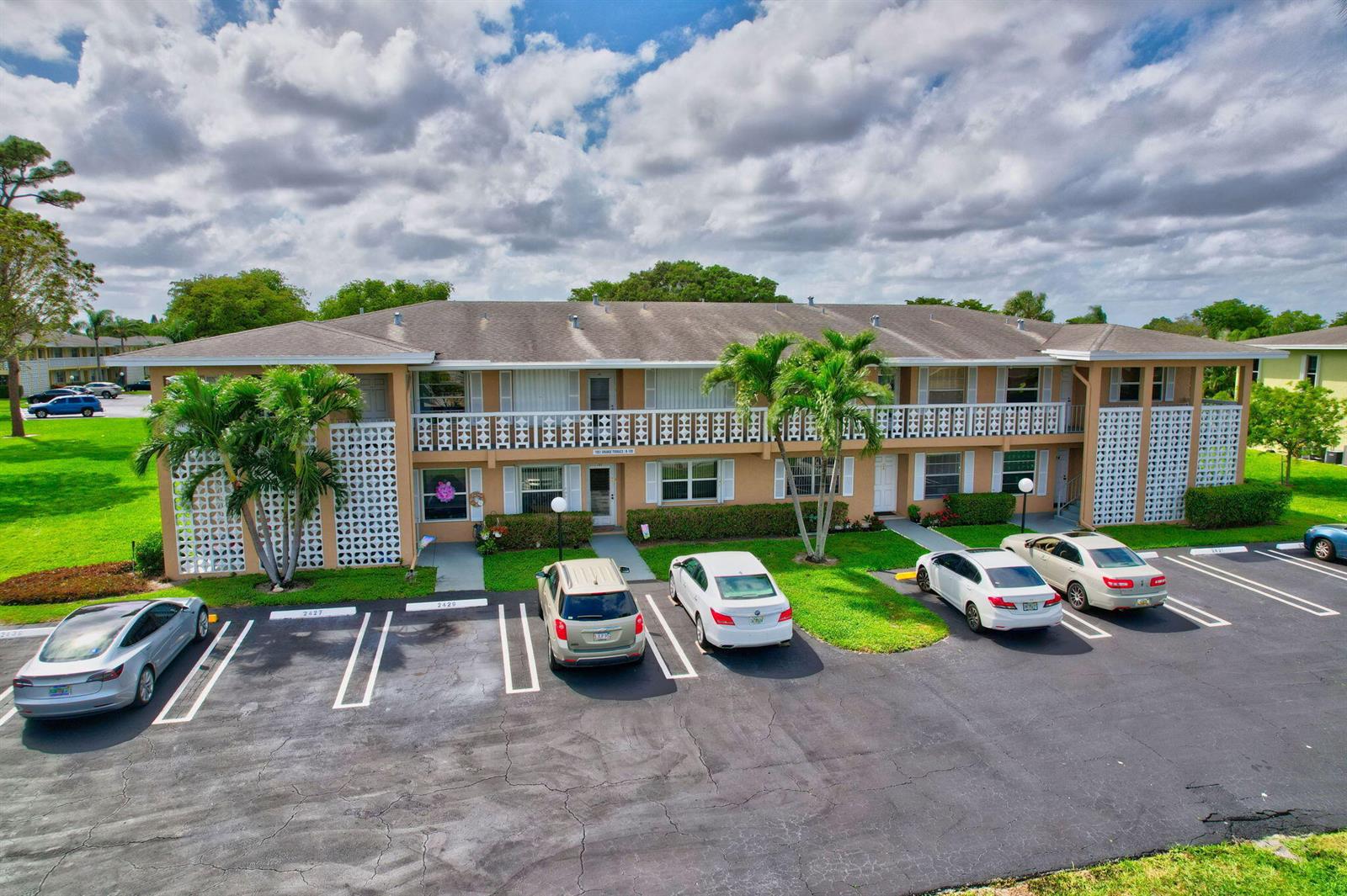 An exterior view of a two-story apartment building with a parking lot in front — 1051 Orange Terrace # 103, Delray Beach FL 33445, DELRAY BEACH, FL