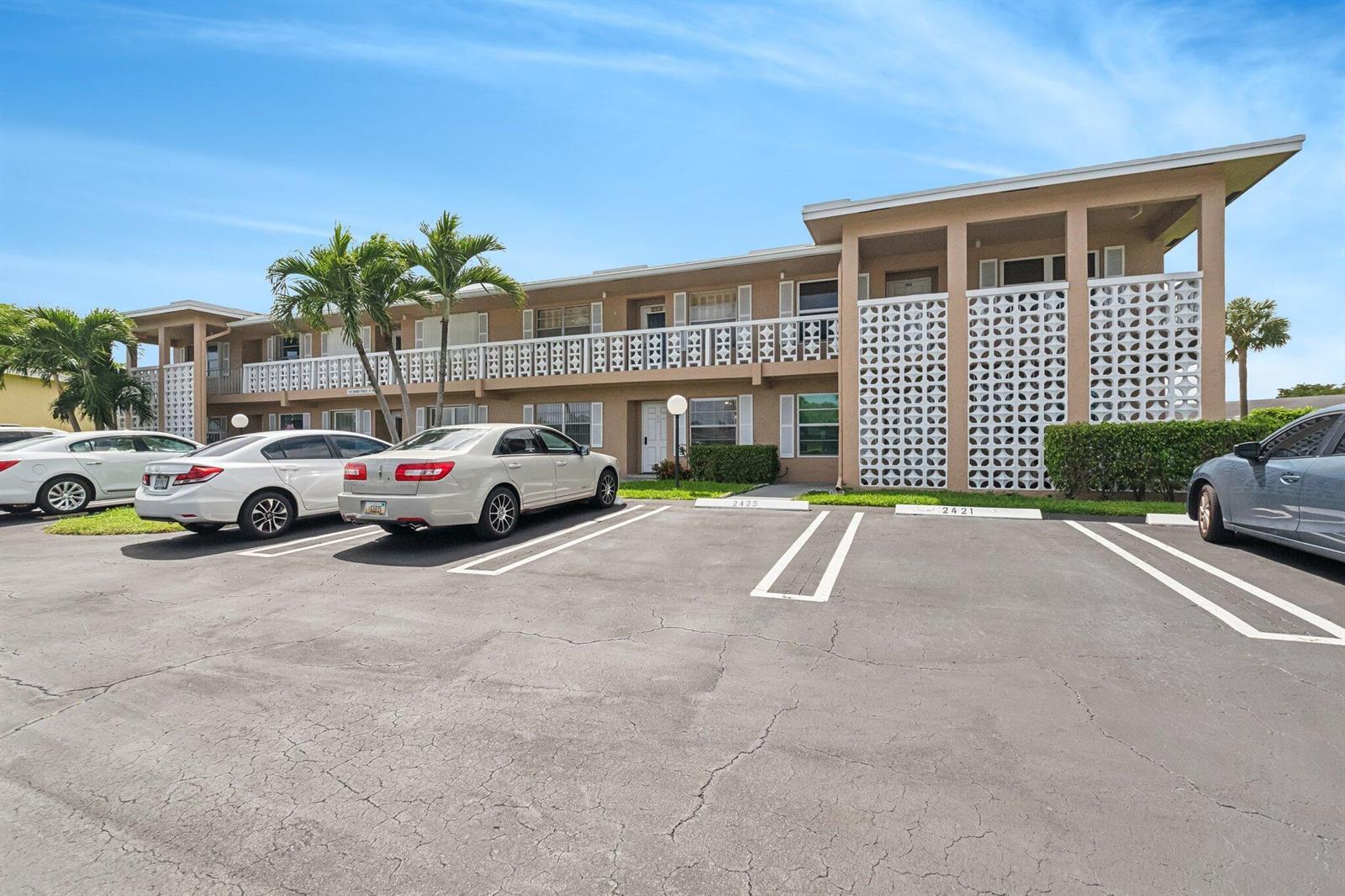 A two-story apartment building features a parking lot, palm trees, and decorative concrete block screens — 1051 Orange Terrace # 103, Delray Beach FL 33445, DELRAY BEACH, FL