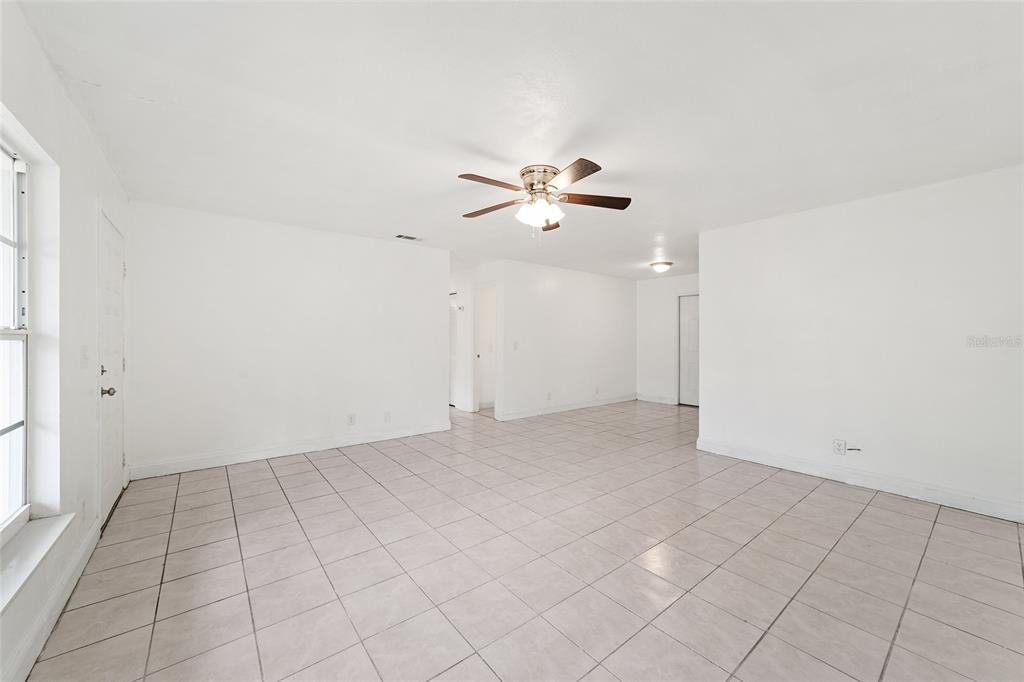 An empty room with white walls, a ceiling fan, and light-colored tile flooring — 2216 NE 38TH STREET, OCALA, FL