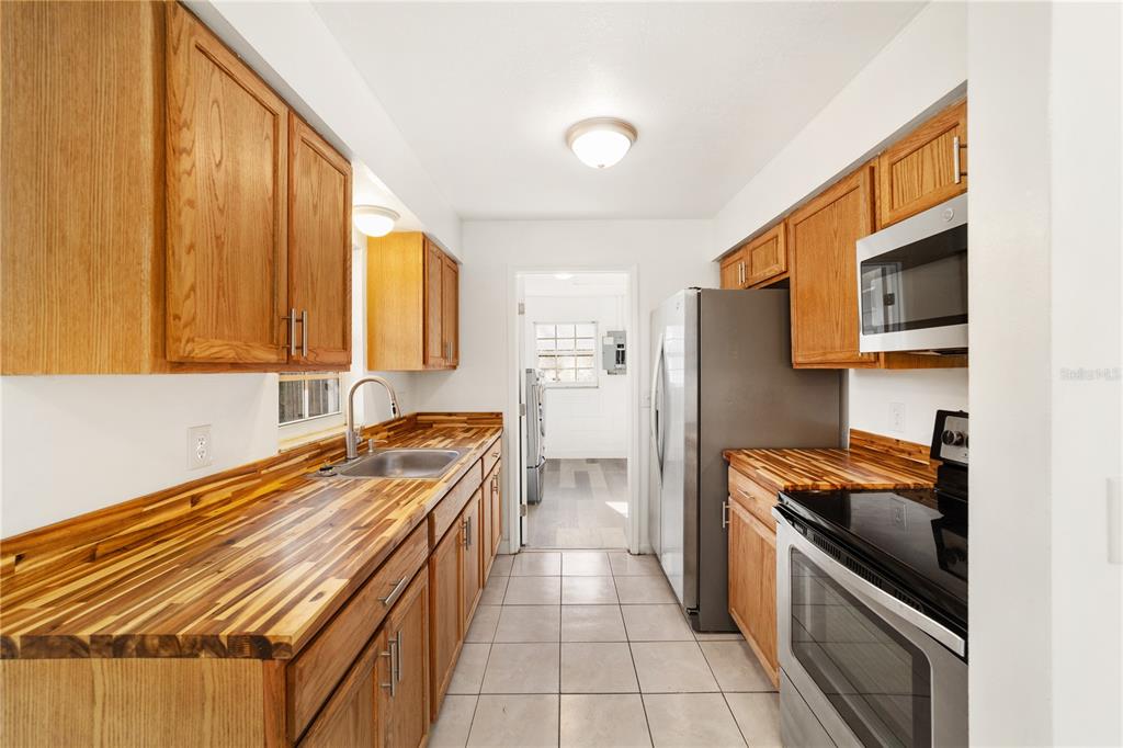 A laundry room features a washer and dryer, gray wood-look flooring, and white block walls — 2216 NE 38TH STREET, OCALA, FL