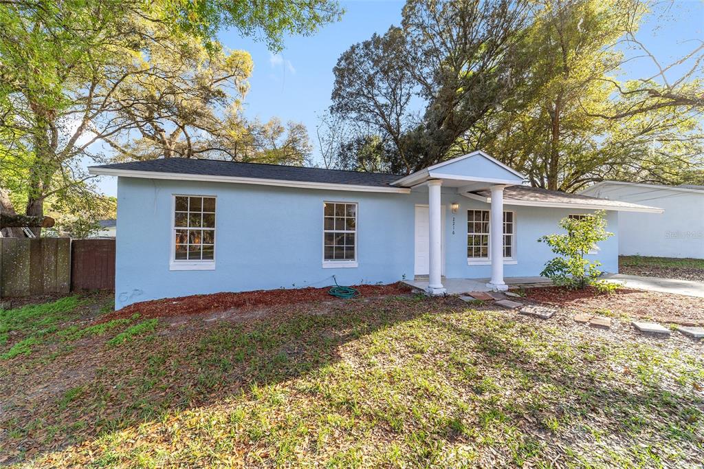 The exterior of a light blue house features a covered entryway with two white columns — 2216 NE 38TH STREET, OCALA, FL