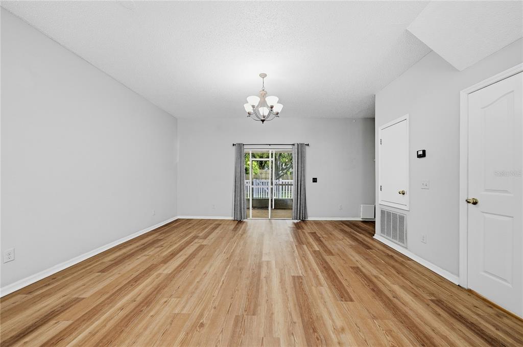 An open-concept living area features wood-look flooring, a kitchen breakfast bar, and a staircase — 10106 BELLEVILLE PLACE, TAMPA, FL
