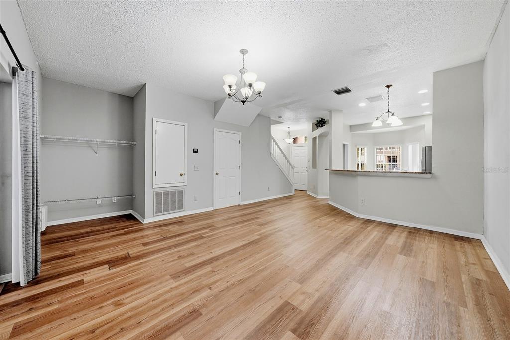 An open-concept living and dining area features light gray walls, wood-look flooring, and two chandeliers — 10106 BELLEVILLE PLACE, TAMPA, FL
