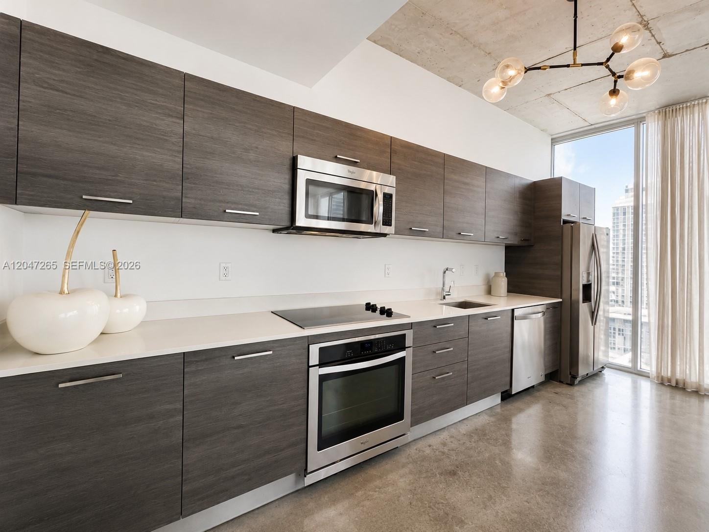 A modern kitchen features dark wood cabinetry, stainless steel appliances, and a concrete ceiling — 151 SE 1st St # 1602, Miami FL 33131, MIAMI, FL